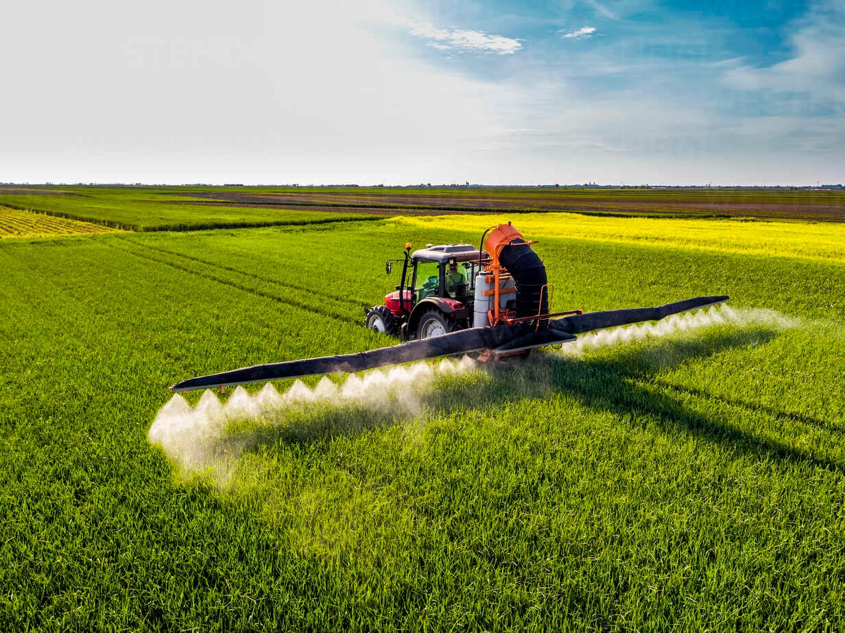 a tractor spraying agrochemical for crop protection in agriculture